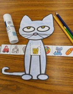 a paper cut out of a cat sitting on top of a wooden table next to markers and pencils