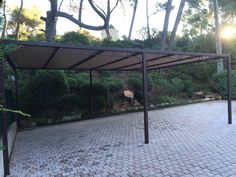 an outdoor covered area with brick pavers and trees