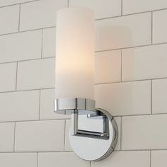 a bathroom light with a white glass shade on the wall next to a brick wall