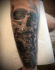 a man's arm with a black and grey skull tattoo on the left leg