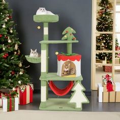 a cat tree with two cats sitting on top of it next to christmas trees and presents