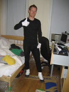 a man standing in front of a bed with white gloves on his hands and feet