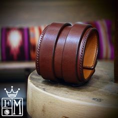 a pair of brown leather bracelets sitting on top of a wooden table