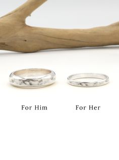 two wedding rings sitting next to each other on top of a white surface with the words for him and her written below them