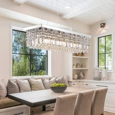 a dining room table with chairs and a bench under a chandelier hanging from the ceiling