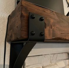 a laptop computer sitting on top of a wooden shelf next to a brick fire place