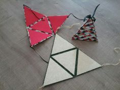 two kites are sitting on the floor next to each other, one red and one white