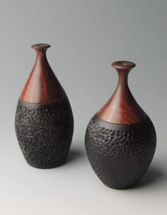 two brown vases sitting next to each other on a gray surface with an intricate design