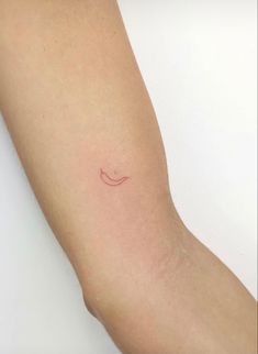 a woman's arm with a small smile tattoo on the left side of her arm