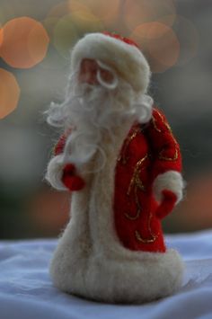 a close up of a santa clause figurine on a table with lights in the background