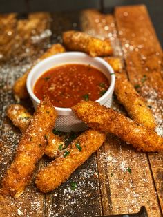 fried fish sticks with dipping sauce on a wooden board next to breaded breadsticks