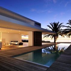 a house with a swimming pool and palm trees in the background at dusk, as seen from outside