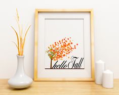 there is a vase with some flowers in it next to a picture frame that says hello fall