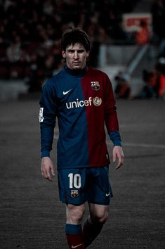 a soccer player in blue and red uniform walking on the field with his foot up