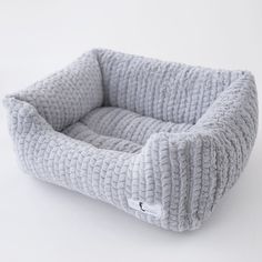 the dog bed is made out of gray fabric and has a square shaped cushion on top