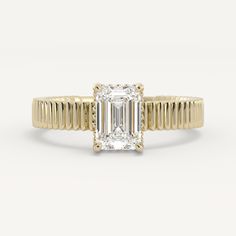 a yellow gold engagement ring with an emerald cut diamond in the center and thin band