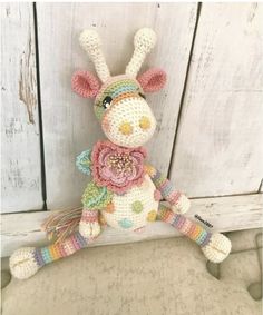 a crocheted stuffed animal sitting on top of a white bench next to a wooden wall