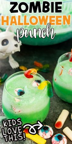 two glasses filled with halloween punch on top of a table next to candy sticks and sprinkles