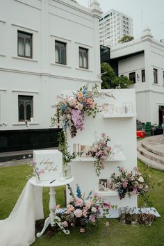 a wedding display in the grass with flowers and photos on it's shelfs