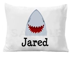 a white pillow with a shark face and the word jared on it's side