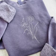 a purple sweater with flowers embroidered on it