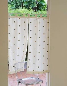 a chair sitting in front of a window with polka dot curtains on it's side