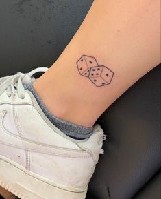 a tattoo on the ankle of a woman's foot with two dice in it