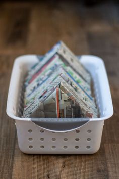 a white container filled with lots of different types of folded papers on top of a wooden table