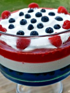 a trifle with berries, cream and blueberries in it on a wooden table