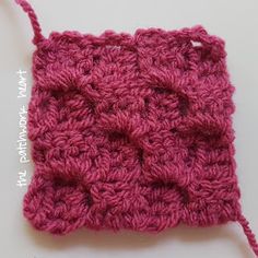 a crochet square is shown in pink yarn