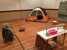 an orange and gray tent sitting on top of a hard wood floor next to a white table