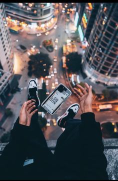 someone is holding up their cell phone in the middle of a city street at night