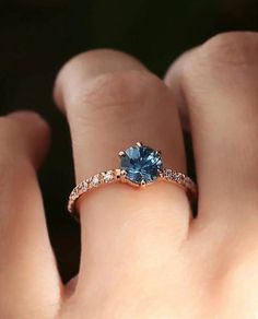 a woman's hand with a ring on it and a blue stone in the middle