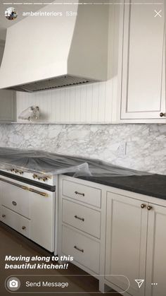 a kitchen with white cabinets and marble counter tops