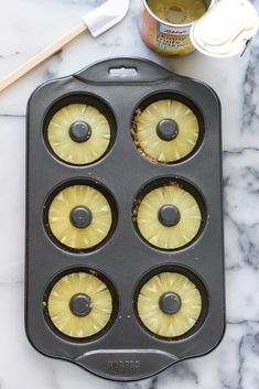 pineapple cupcakes in a muffin tin next to a can of tea