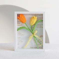 there are three crocheted flowers in a card with a ribbon tied around it