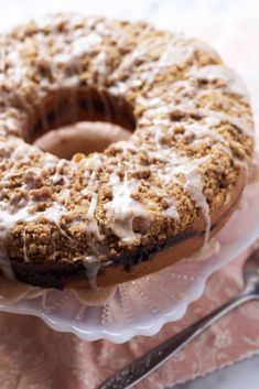 a frosted donut sitting on top of a cake plate next to a fork