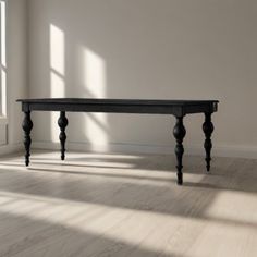 an empty room with a wooden table in the middle and sunlight coming through the window