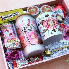 a pink box filled with lots of different types of food and drink items on top of a table