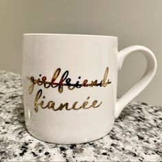 a white coffee mug with gold lettering on it