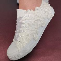 a woman's feet wearing white shoes with flowers on the bottom and lace detailing