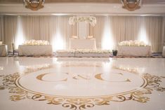 the floor is decorated with white flowers and gold trimmings for a wedding reception