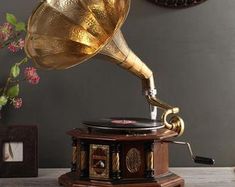 an old phonograph sitting on top of a table next to a vase with flowers