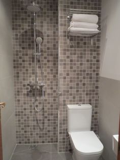 a toilet and shower in a small bathroom with tile on the walls, flooring and wall coverings