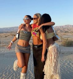 three beautiful women standing next to each other in the sand