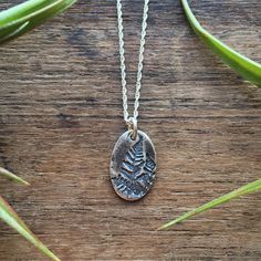 Fern Necklace in Sterling Silver.  Sterling silver rustic, artisan oval fern charm. Oxidized imprint for contrast. Detailed fern. Classic, rustic design. Your choice of 16" or 18" rope chain.  Measurements of pendant: 3/4" long and 7/16" wide. Made in and shipped from Tupper Lake, New York, Adirondack Mountains. Rustic Silver Oval Jewelry, Nature-inspired Oval Engraved Necklace, Sterling Silver Hand Stamped Oval Pendant Jewelry, Sterling Silver Oval Necklace With Nature-inspired Style, Nature-inspired Oval Engraved Necklaces, Silver Oval Pendant Jewelry Hand Stamped, Silver Hand Stamped Oval Pendant Jewelry, Rustic Sterling Silver Engraved Necklaces, Silver Engraved Nature-inspired Necklace