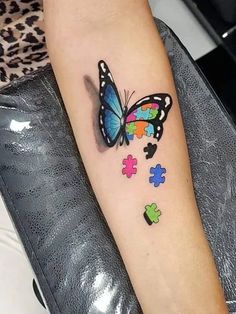 a colorful butterfly tattoo on the left inner forearm and wrist with puzzle pieces all over it