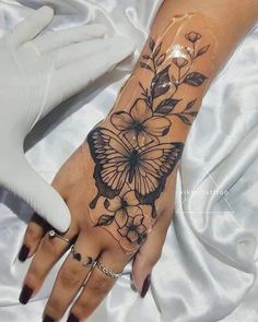 a woman's hand with a butterfly tattoo on it and flowers around the wrist