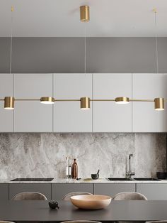 a modern kitchen with marble counter tops and gold pendant lights hanging from the ceiling over the dining room table