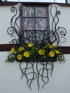 the window is decorated with flowers and wrought iron work on it's side wall